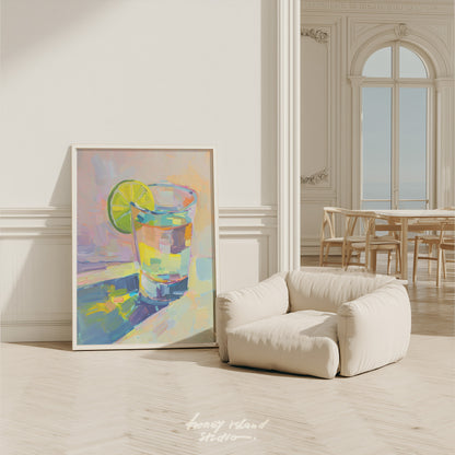 Colorful abstract painting of a tequila glass with a lime on a white wall in a room with a beige armchair.