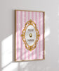 Decorative wall art with pink striped background and gold frame on a white wall.