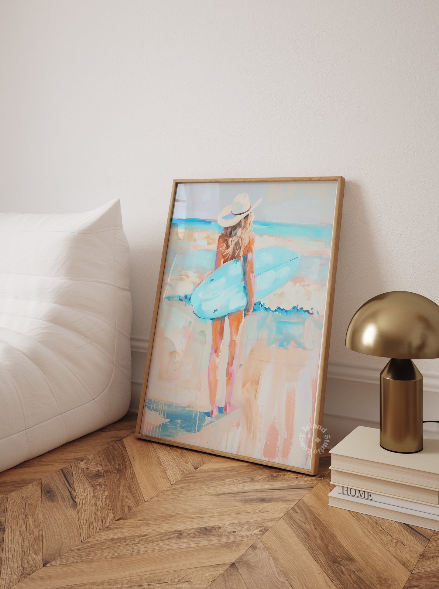 Framed artwork of a woman in a blue dress on a wall next to a lamp and books.