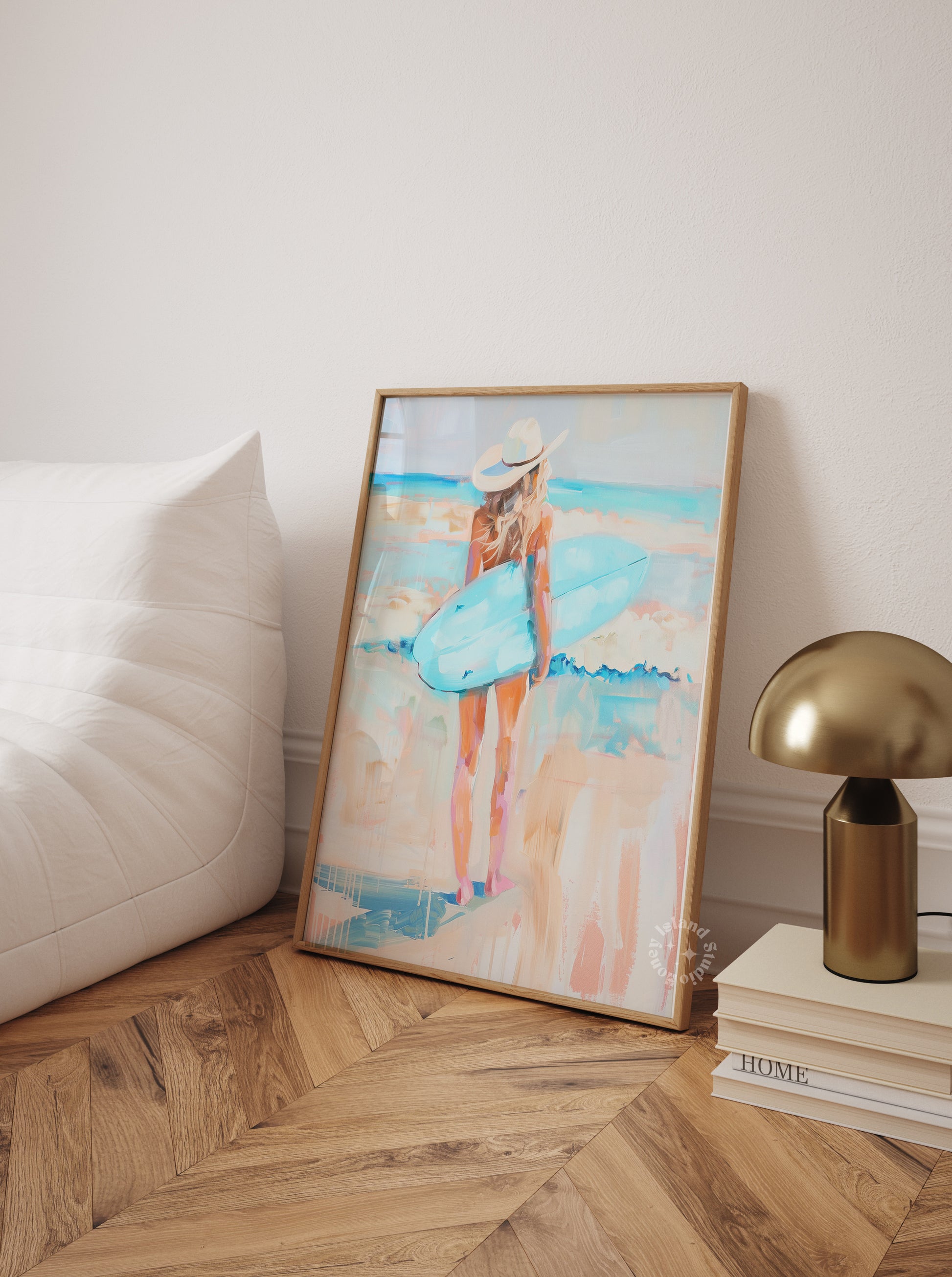 Framed artwork of a woman in a blue dress on a wall next to a lamp and books.