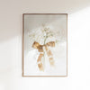 Framed artwork of white flowers with a gold bow on a light background
